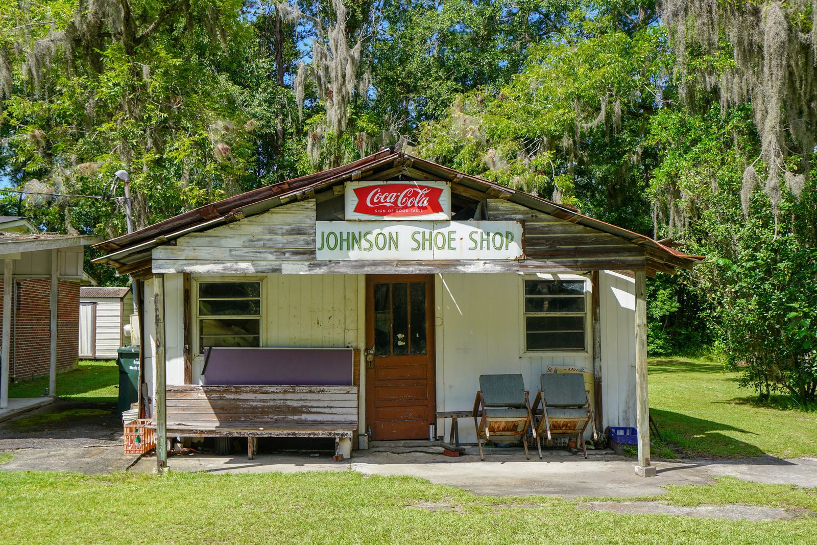 Small historic shop building beneath oak trees draped with Spanish moss in Long County, Georgia