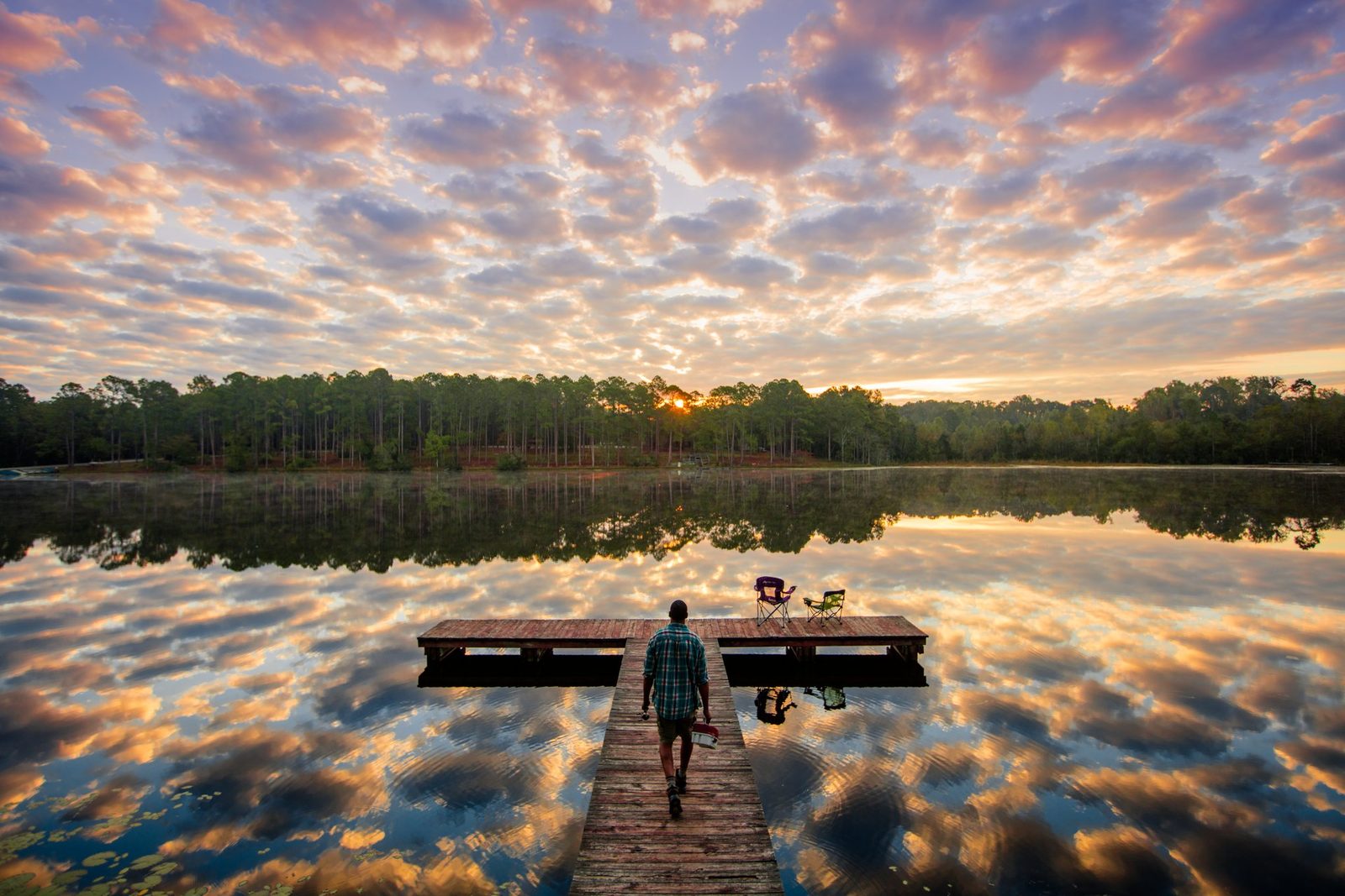 Person walking along a dock over a still lake at sunrise, Gordonia-Alatamaha State Park, Tattnall County